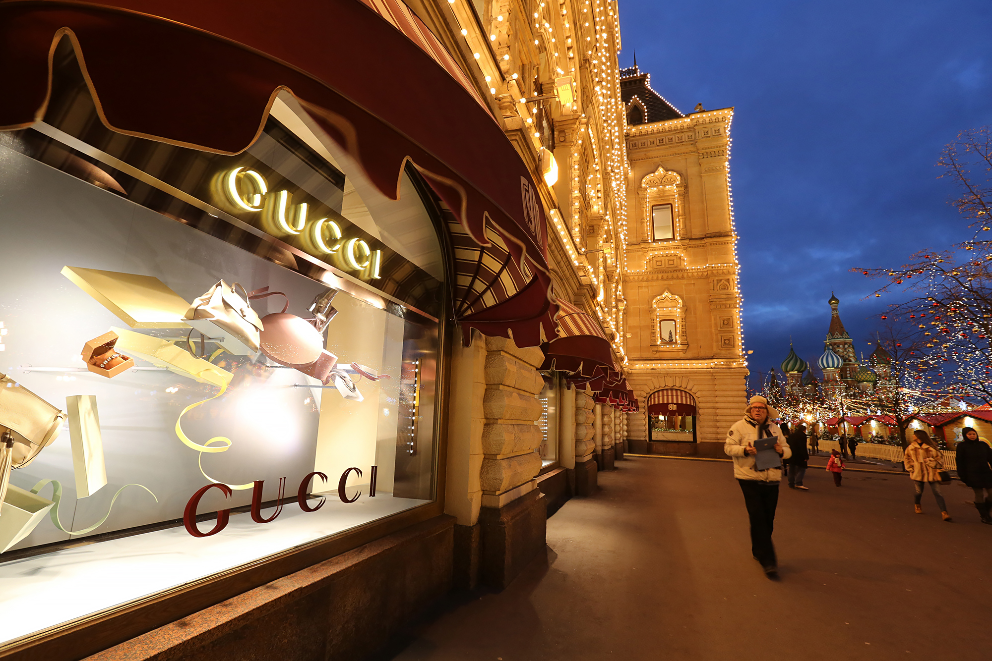 Pedestrians pass a display of Gucci luxury products, a unit of Kering SA, in the windows of the GUM department store on Red Square in Moscow, Russia, on Monday, Dec. 22, 2014. The ruble's rout, sparked by falling oil prices and sanctions imposed on businesses including OAO Sberbank, prompted Russians to begin buying luxury goods from Porsche sports cars to Tiffany rings to preserve the value of their savings. Photographer: Andrey Rudakov/Bloomberg via Getty Images